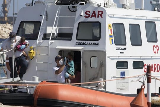 Sanitäter tragen in Pozzallo (Sizilien) Kinder von Bord eines Schiffes der italienischen Küstenwache.