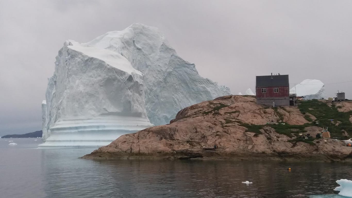 Ein Eisberg liegt vor dem Dorf auf Grund: Ein Dorf im Westen Grönlands ist der Bedrohung eines großen Eisberges ausgesetzt.