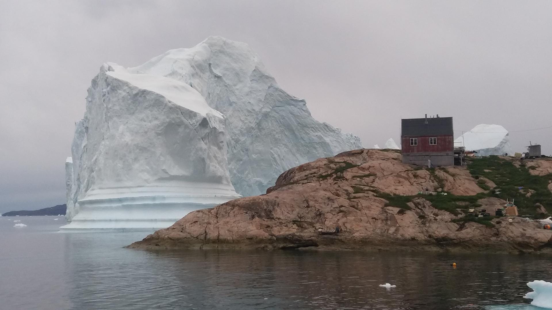 Ein Eisberg liegt vor dem Dorf auf Grund: Ein Dorf im Westen Grönlands ist der Bedrohung eines großen Eisberges ausgesetzt. Ein Eisberg liegt vor dem Dorf auf Grund: Ein Dorf im Westen Grönlands ist der Bedrohung eines großen Eisberges ausgesetzt.