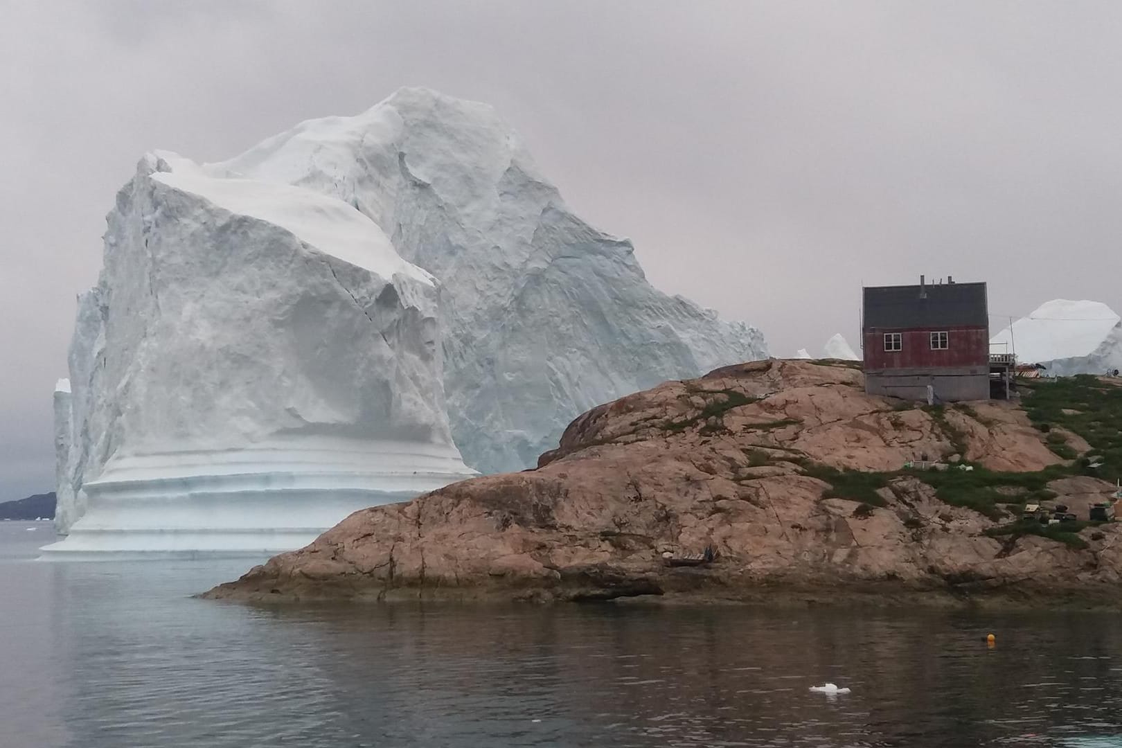 Ein Eisberg liegt vor dem Dorf auf Grund: Ein Dorf im Westen Grönlands ist der Bedrohung eines großen Eisberges ausgesetzt.