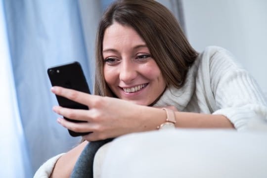 Frau mit Smartphone: Rund 18,2 Millionen Menschen spielen inzwischen mehr oder weniger regelmäßig auch auf ihrem Smartphone Videospiele.