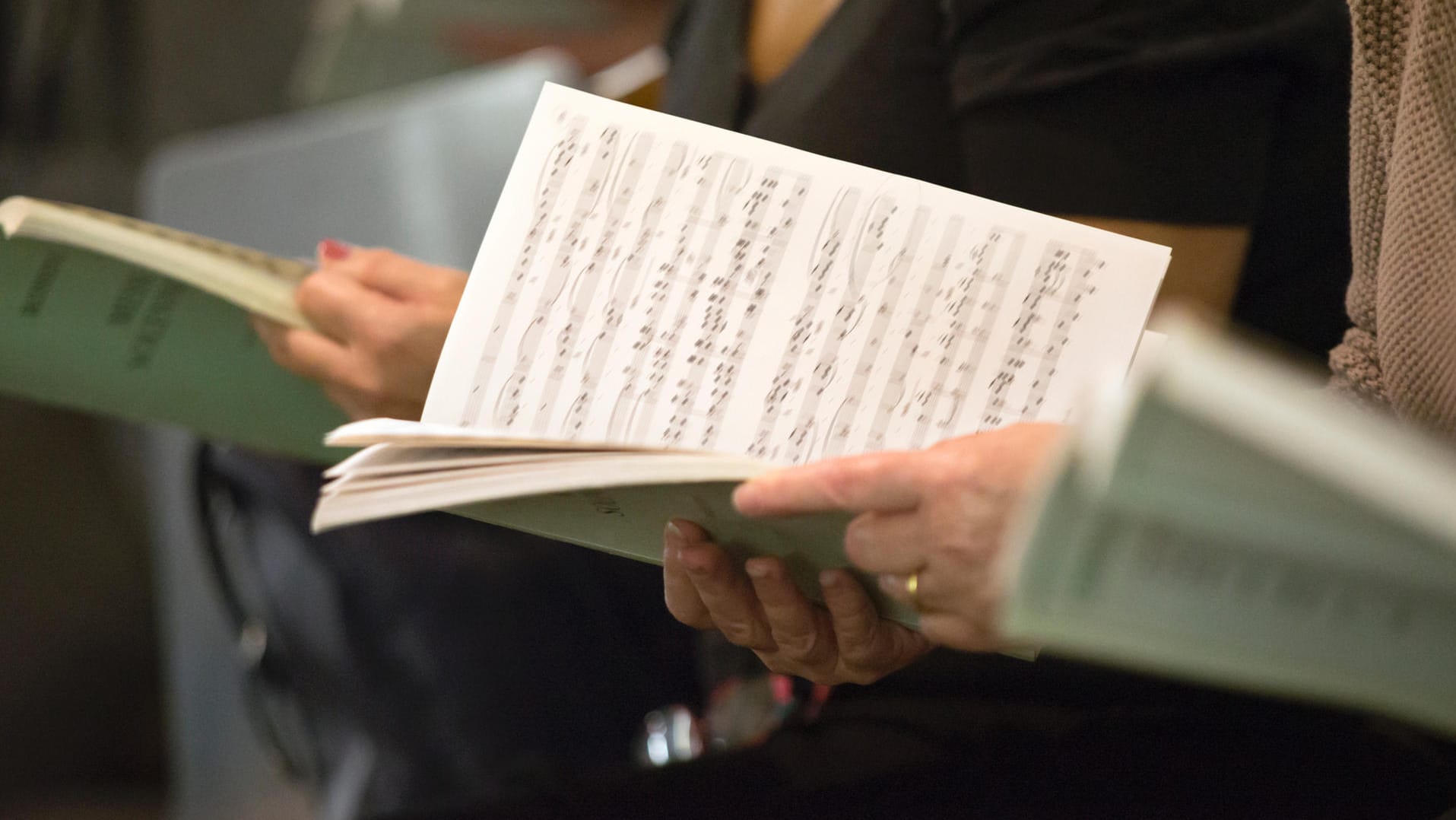 Chorsängerin mit Noten: Das gemeinsame Singen mit Kollegen steigert den Teamgeist und macht Spaß, meint das Bundesministerium für Forschung und Bildung.