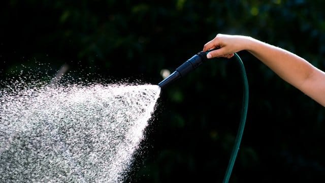 Frau hält Gartenschlauch Frau hält Gartenschlauch