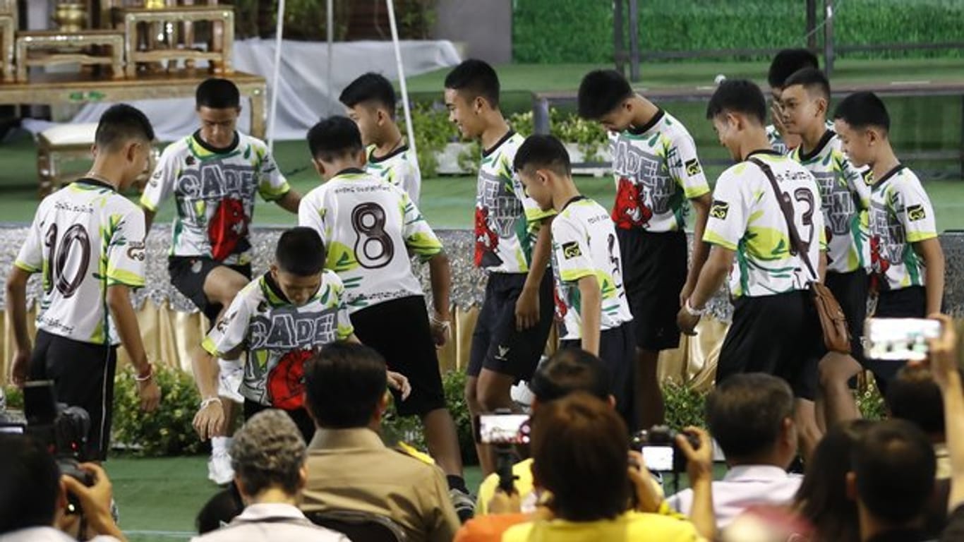 Die Jungen der geretteten Fußballmannschaft dribbeln mit ihrem Trainer auf einem Mini-Fußballplatz.