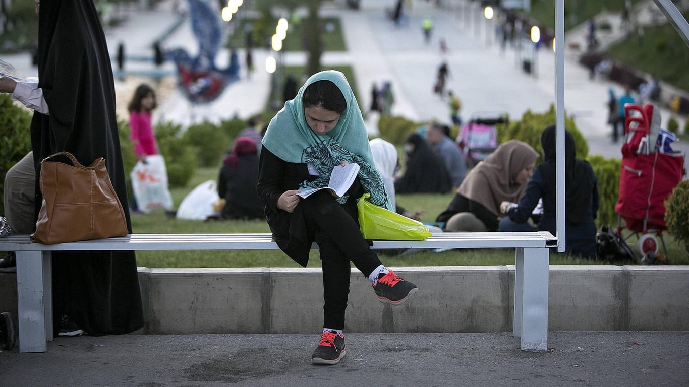 Ein Frau sitzt lesend auf einer Bank in Teheran: Seit 40 Jahren gibt es gesetzliche Regelungen für die Kleidung von Frauen im Iran. (Archivbild)
