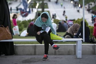 Ein Frau sitzt lesend auf einer Bank in Teheran: Seit 40 Jahren gibt es gesetzliche Regelungen für die Kleidung von Frauen im Iran. (Archivbild)