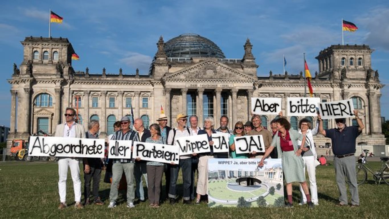 Anhänger des Vereins Berliner Historische Mitte demonstrieren auf der Wiese vor dem Reichstagsgebäude.