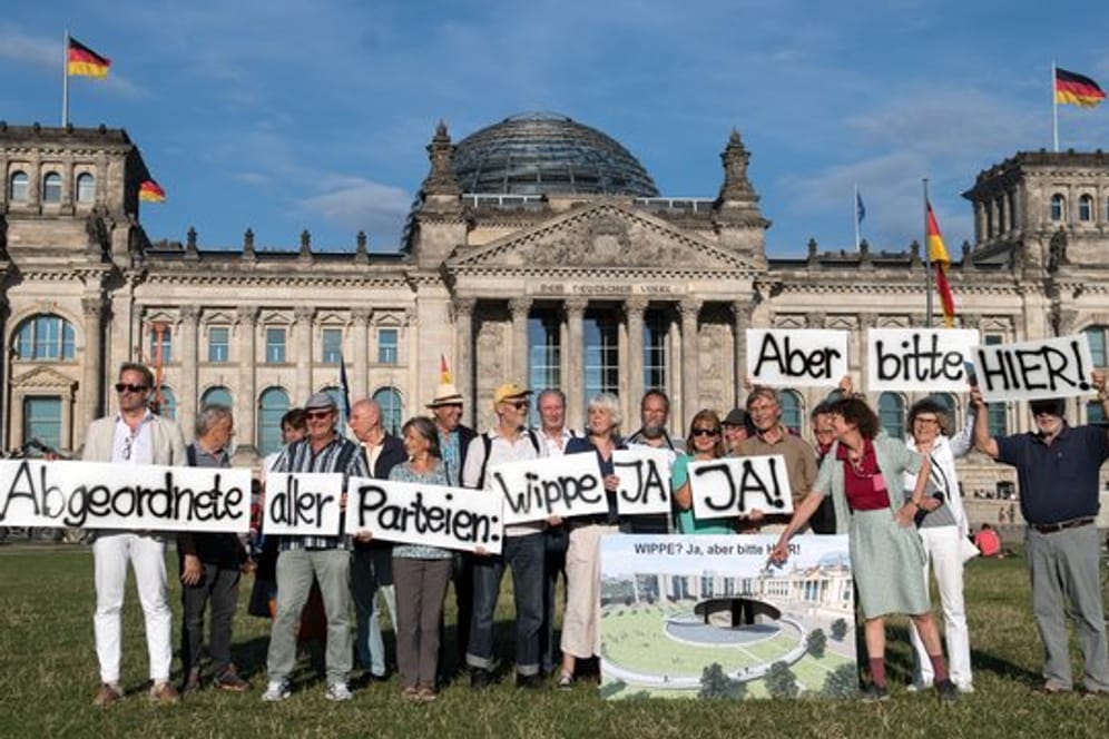 Anhänger des Vereins Berliner Historische Mitte demonstrieren auf der Wiese vor dem Reichstagsgebäude.