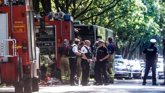 Einsatzkräfte stehen vor dem Bus im Lübecker Stadtteil Kücknitz, in dem ein Fahrgast Mitreisende mit einem Messer attackiert hatte.