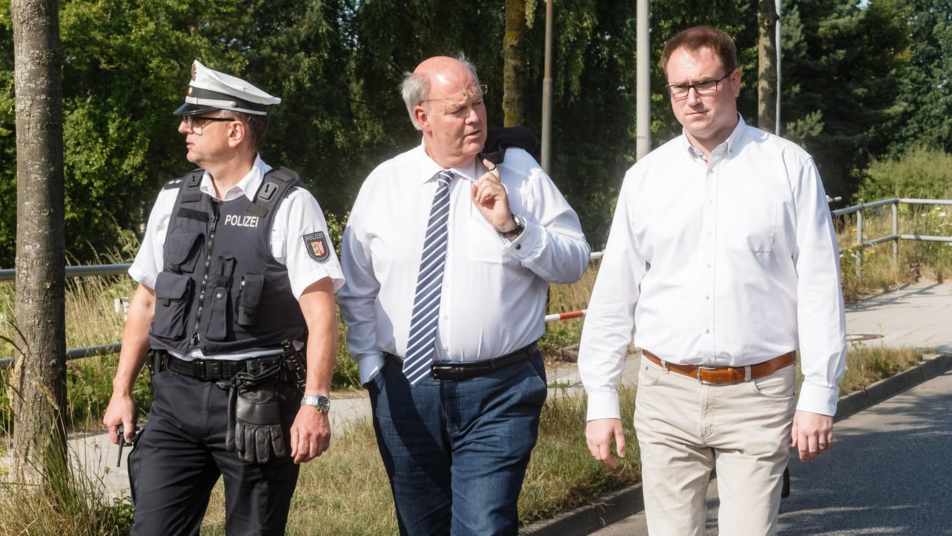 Hans-Joachim Grote (CDU, M), Innenminister Schleswig-Holsteins, und Jan Lindenau (SPD, r), Bürgermeister von Lübeck, gehen mit einem Polizeivertreter zum Tatort.
