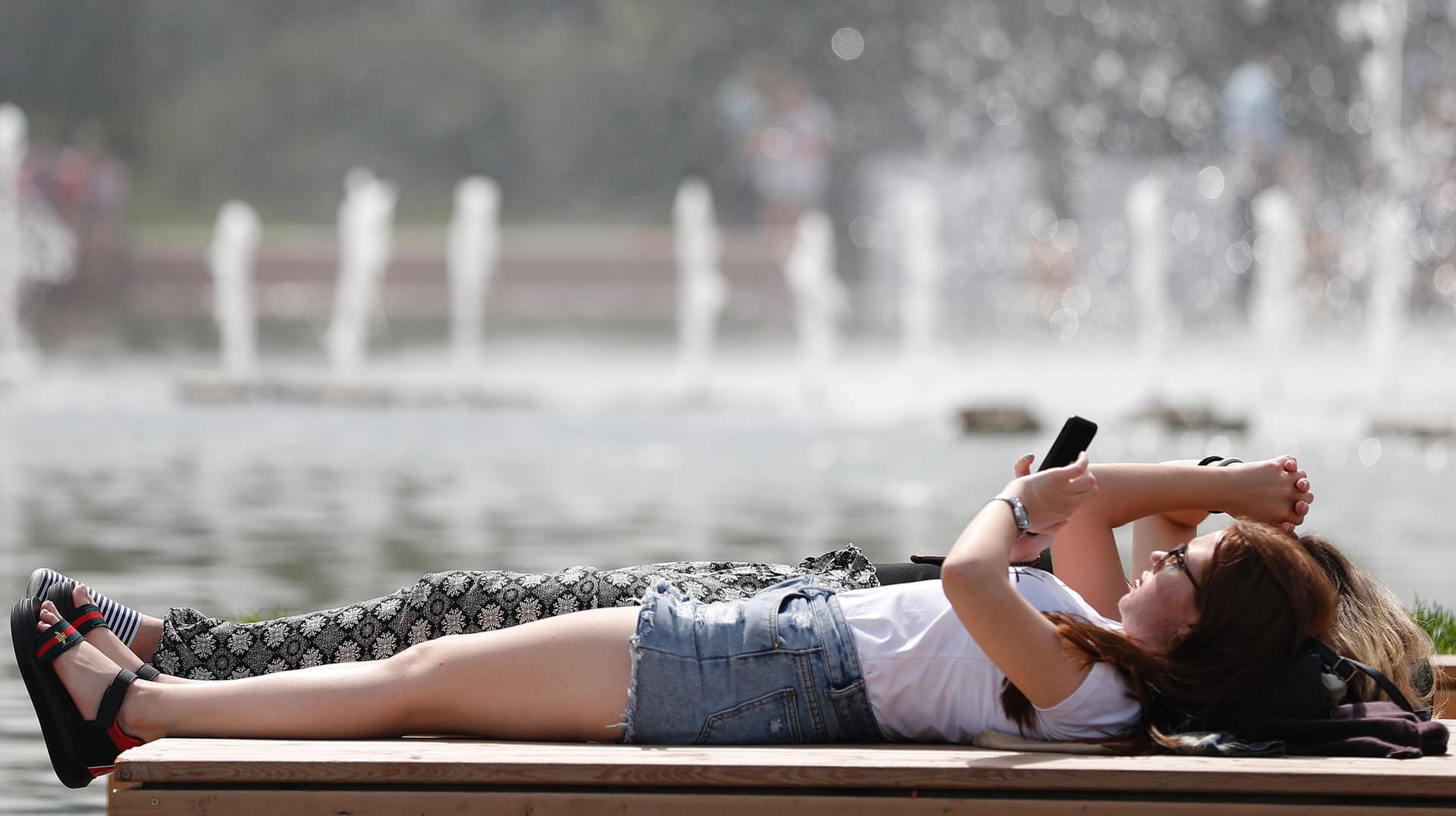 Der Hochsommer ist da: Zwei Frauen sonnen sich auf einer Bank.