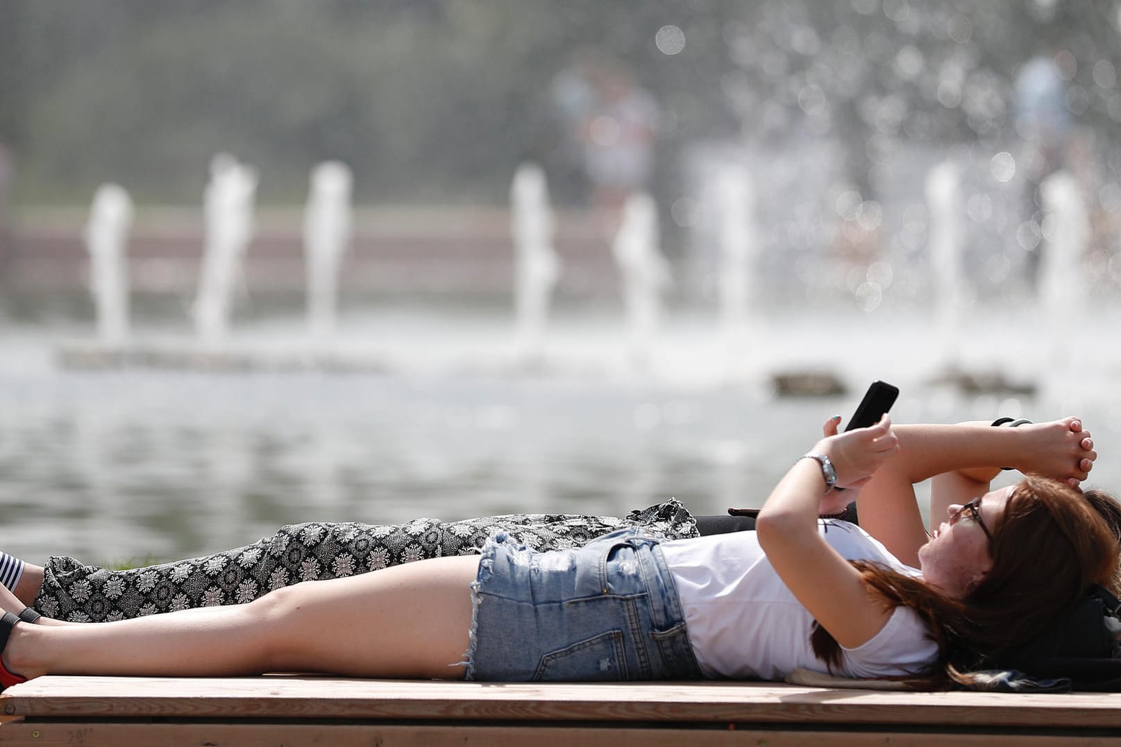 Der Hochsommer ist da: Zwei Frauen sonnen sich auf einer Bank.