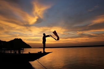 Indien, Guwahati: Ein Bootsmann trocknet im Sonnenuntergang seine Kleidung am Ufer des Brahmaputra-Flusses.