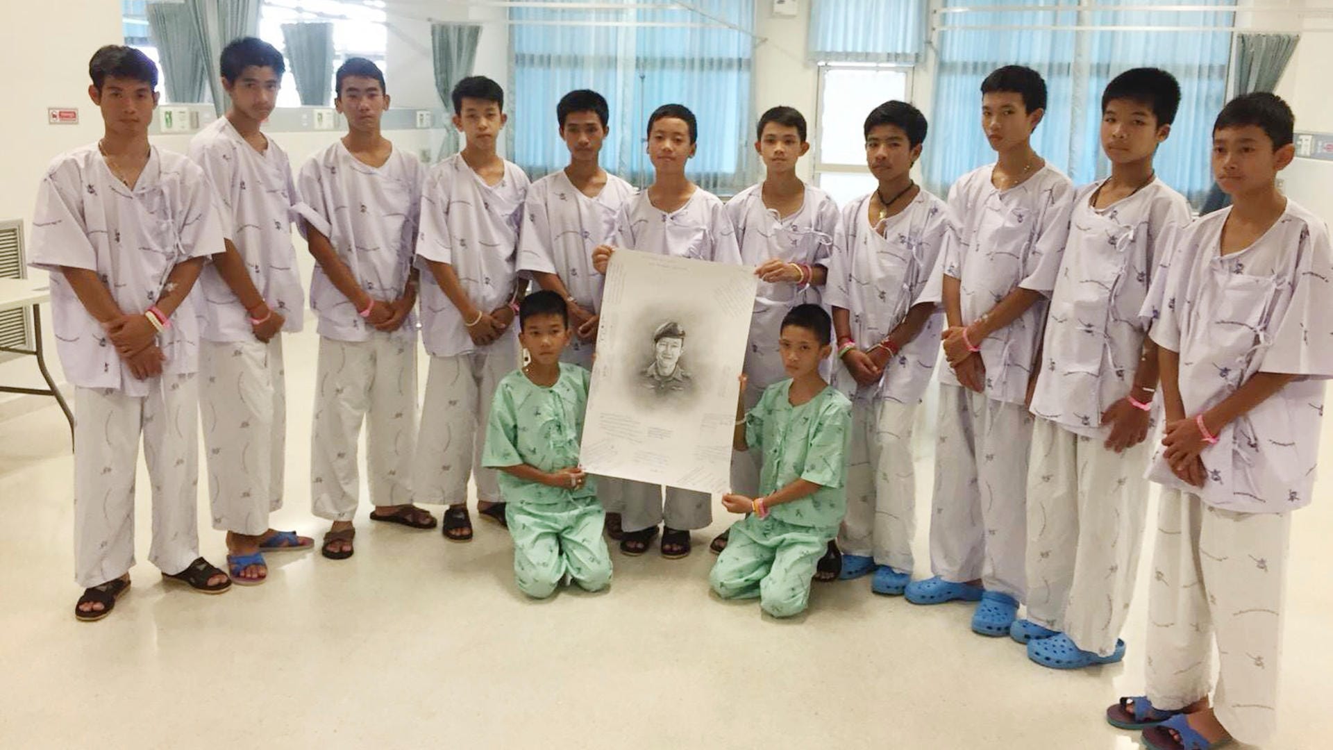 Die geretteten Jungen mit einem Bild des Tauchers der Thai Navy Seals, der bei ihrer Befreiung gestorben ist: In einem Kloster sollen die Jungen zu Novizen ernannt werden.