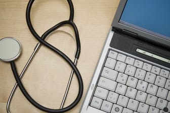 Ein Stethoskop liegt neben einem Laptop.