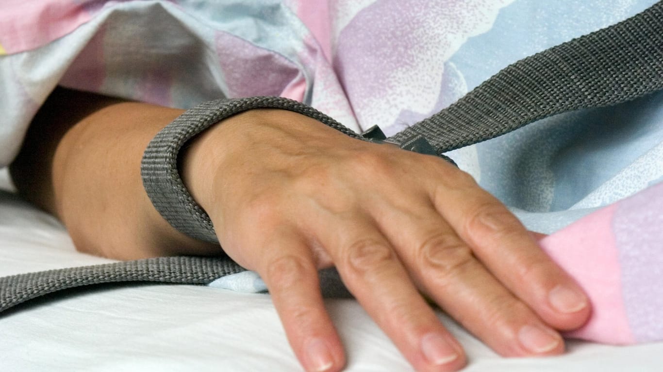 Mit einem Riemen festgebundene Hand eines Patienten