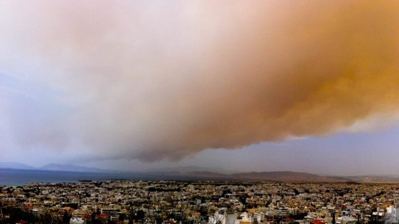 Eine Rauchwolke färbt Teile des Himmels über Athen orange.