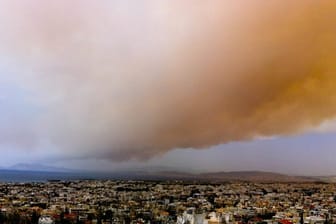 Eine Rauchwolke färbt Teile des Himmels über Athen orange.