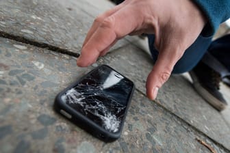 Typischer Unfall: Ein Sturz auf den Asphalt - schon ist das Smartphone-Display kaputt: Bei Gorilla-Glas soll das zumindest seltener vorkommen.