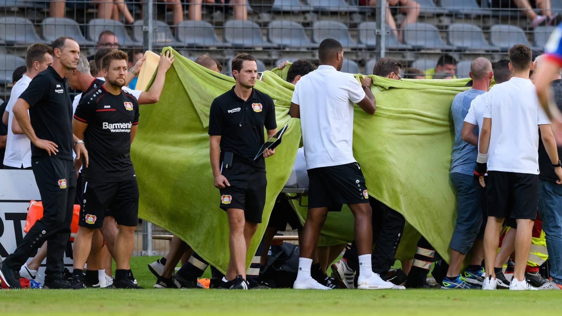 Karim Bellarabi wird behandelt, seine Teamkollegen schirmen ihn ab.