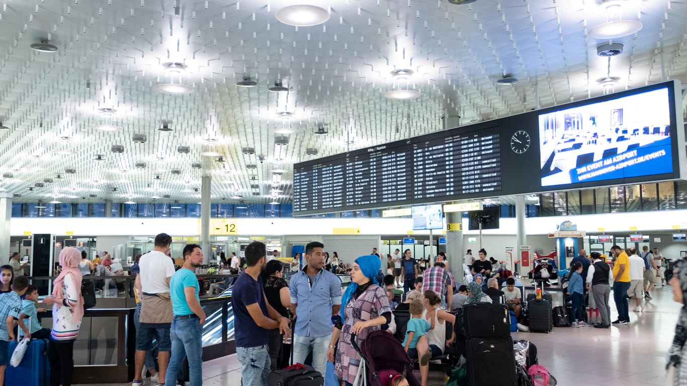 Fluggäste stehen in einer Halle des Flughafen vor einer Abfluganzeigetafel: Der Flughafen von Hannover ist wegen Hitzeschäden gesperrt worden.