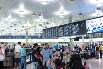 Fluggäste stehen in einer Halle des Flughafen vor einer Abfluganzeigetafel: Der Flughafen von Hannover ist wegen Hitzeschäden gesperrt worden.