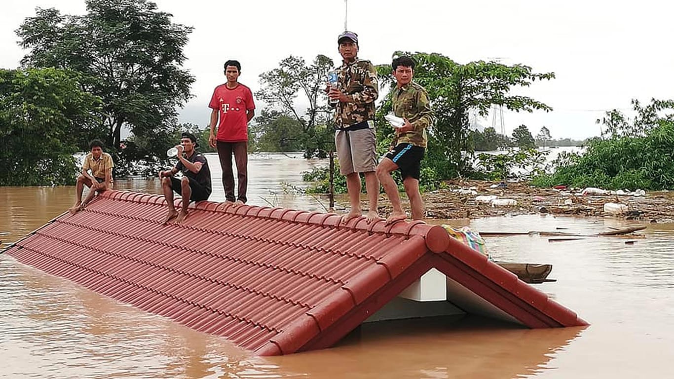 Dorfbewohner retten sich vor der Flut auf ein Hausdach: Acht Dörfer und mehr als 6000 Menschen sind von dem Dammbruch in Laos betroffen. Die Zahl der Vermissten ist weiterhin unklar.