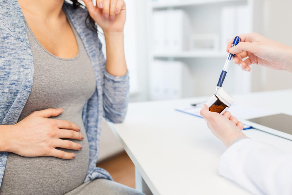 Schwangere Frau beim Arzt wird über Medikamente beraten