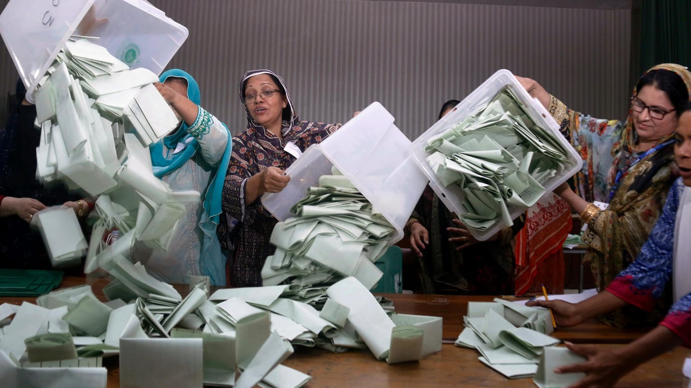 Wahlhelfer leeren in einem Wahllokal Wahlurnen und beginnen Stimmen zu zählen.