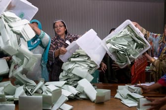 Wahlhelfer leeren in einem Wahllokal Wahlurnen und beginnen Stimmen zu zählen.
