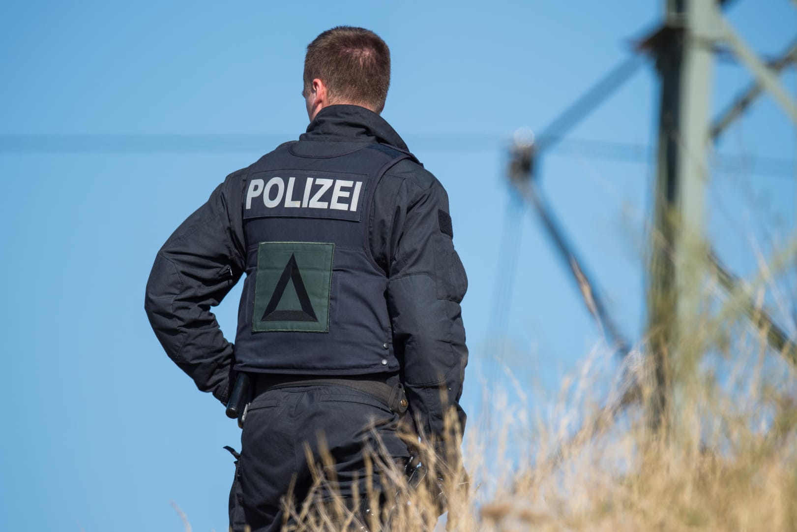 Ein Polizist steht an einem Gleisabschnitt in Richtung Weimar: Seit Donnerstagmorgen sucht die Polizei den mutmaßlichen Messerstecher.