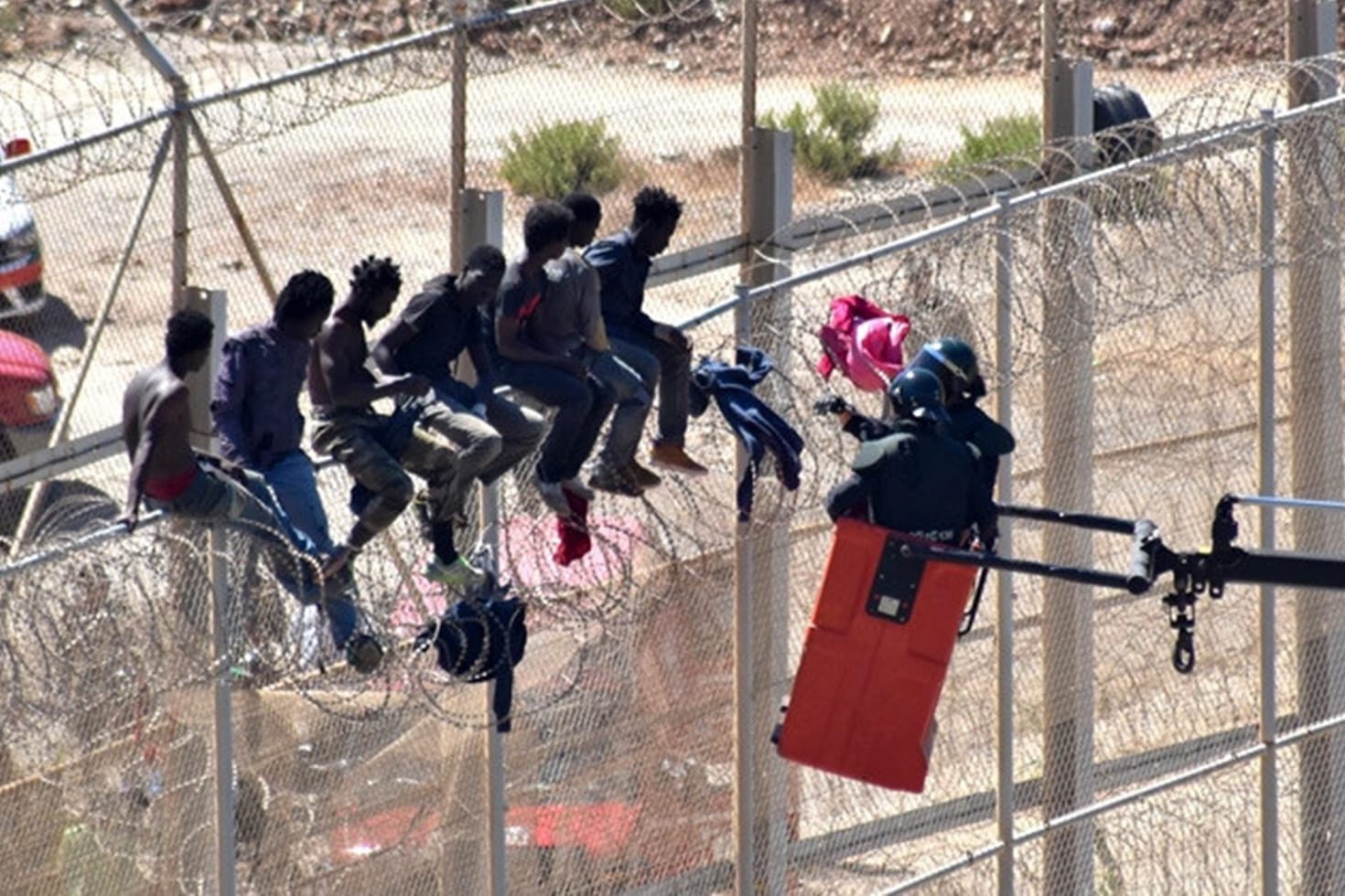 Migranten sitzen auf dem Grenzzaun in Ceuta, der die spanische Enklave von Marokko trennt: Spanien will die messerscharfen Klingen von den Zäunen entfernen.