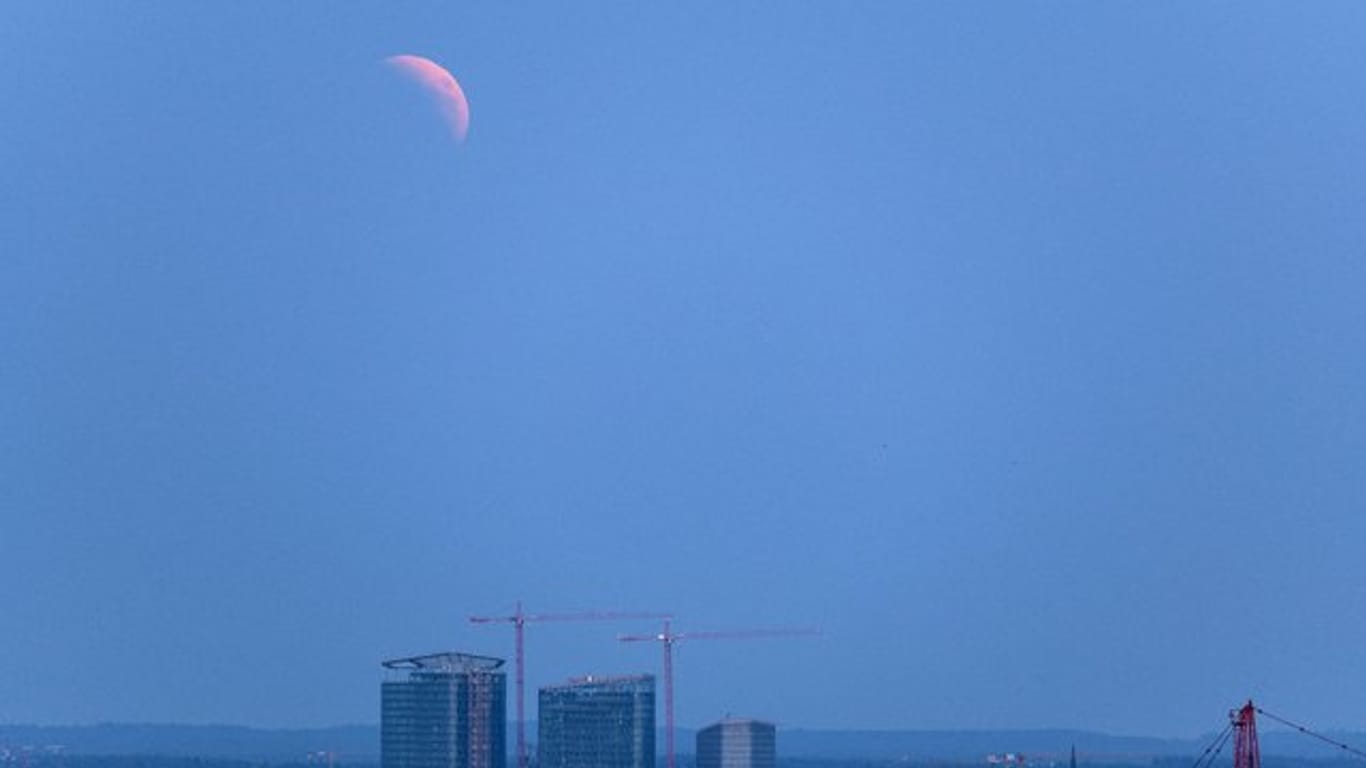 Der aufgehende Mond ist im Dunst über München zu sehen.