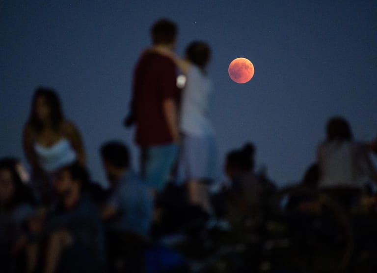 Ein Spektakel für die Masse: Zahlreiche Menschen beobachten am Olympiaberg in München die Mondfinsternis mit dem rötlichen Vollmond.