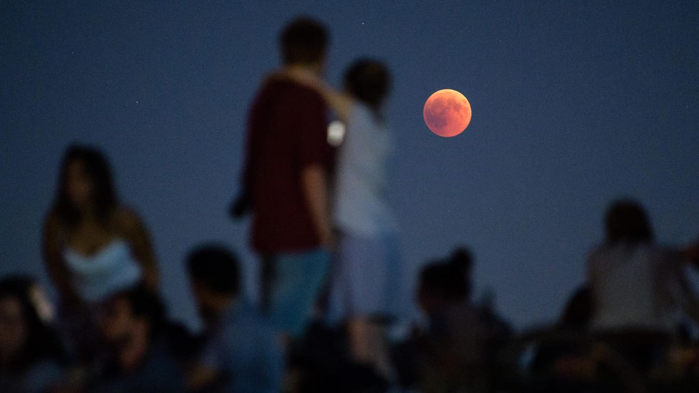 Ein Spektakel für die Masse: Zahlreiche Menschen beobachten am Olympiaberg in München die Mondfinsternis mit dem rötlichen Vollmond.