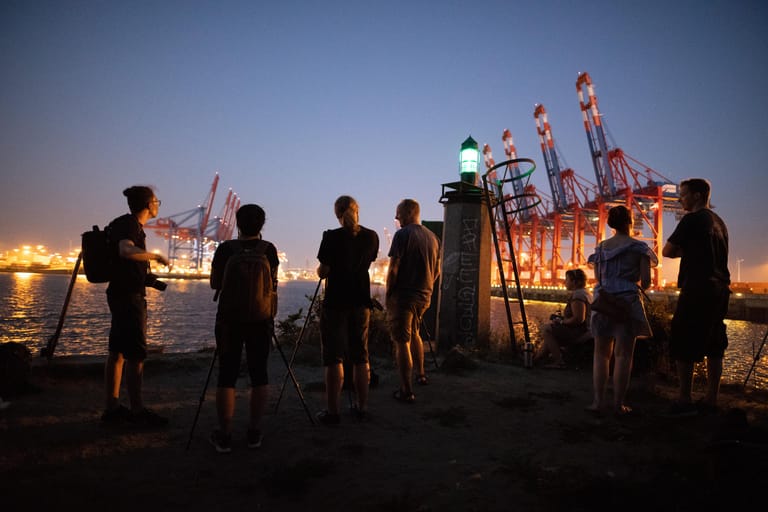 Hamburg: Schaulustige stehen mit Kameras im Hamburger Hafen und warten auf den aufgehenden Mond.