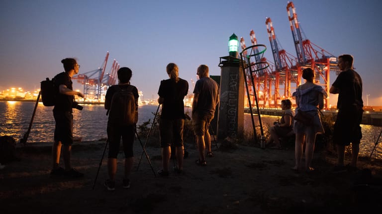 Hamburg: Schaulustige stehen mit Kameras im Hamburger Hafen und warten auf den aufgehenden Mond.