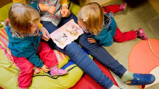 Frau liest mit zwei Kindern ein Buch