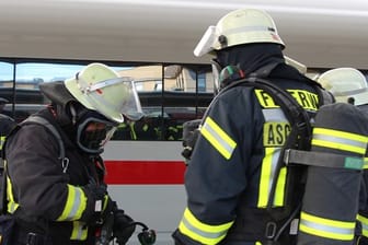 Nach Fund von Petrischale: Feuerwehrleute mit Atemschutzmasken stehen vor einem ICE