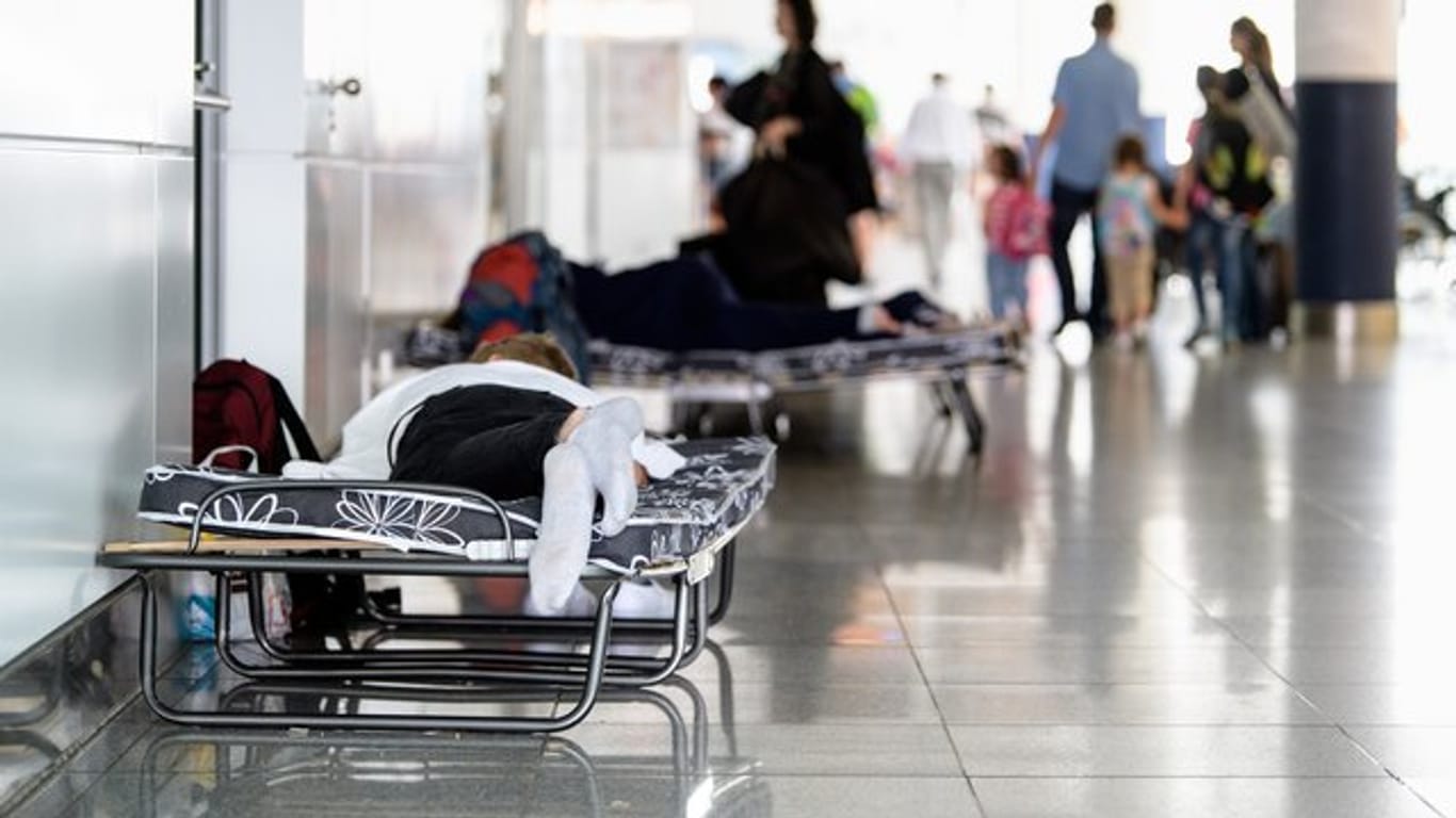 Fluggäste schlafen auf Klappbetten am Flughafen in München.