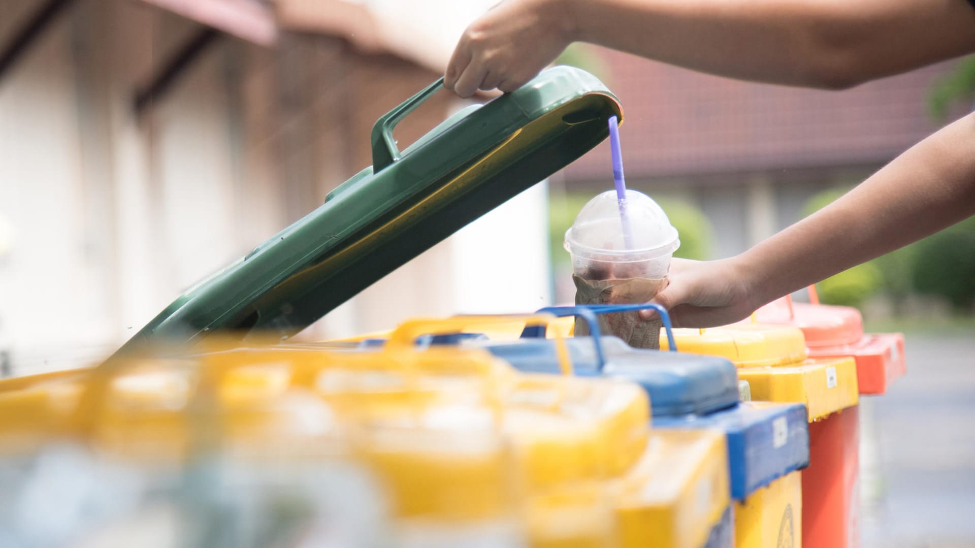 Kind wirft Plastikbecher in den Müll