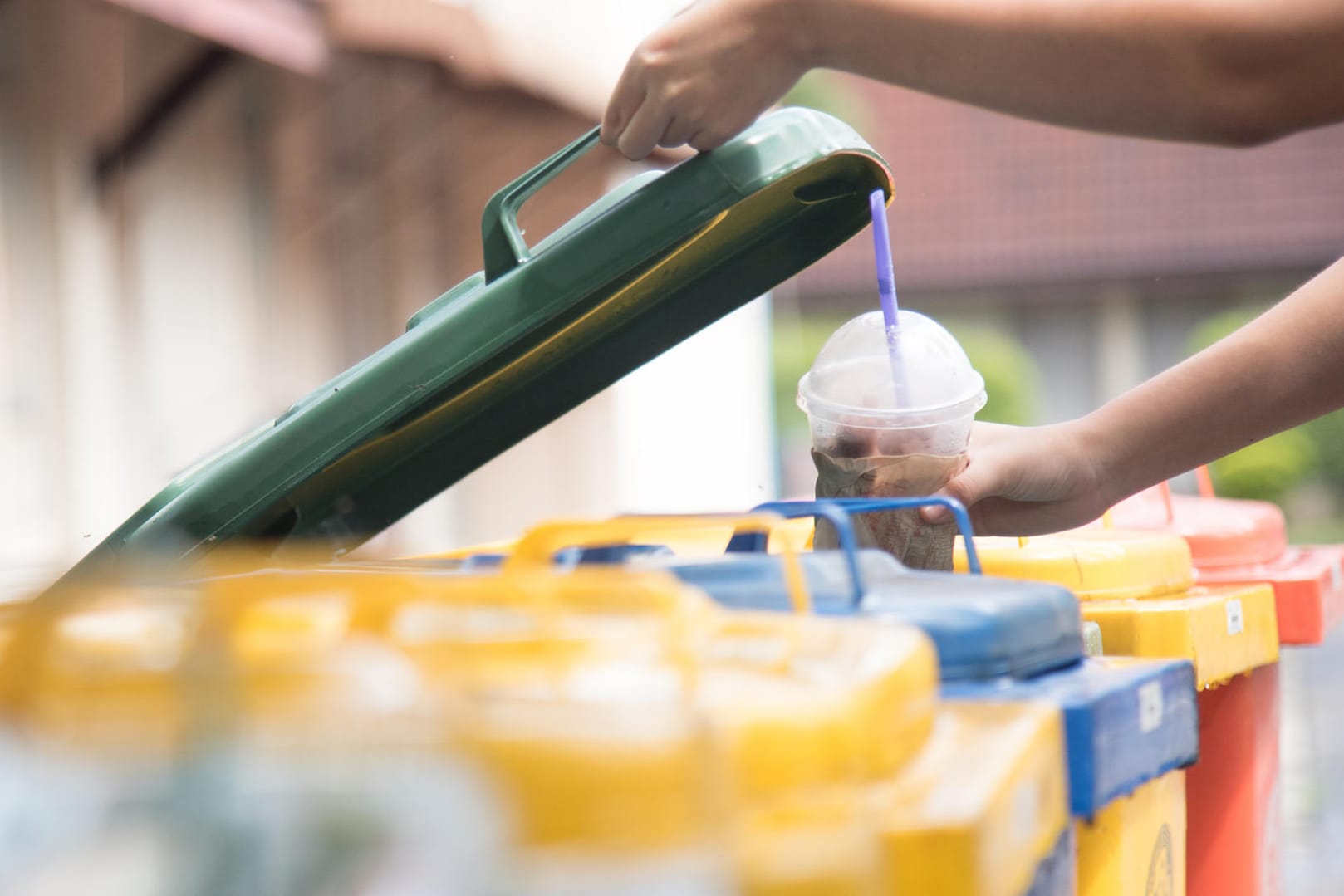 Kind wirft Plastikbecher in den Müll