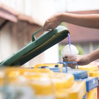Kind wirft Plastikbecher in den Müll