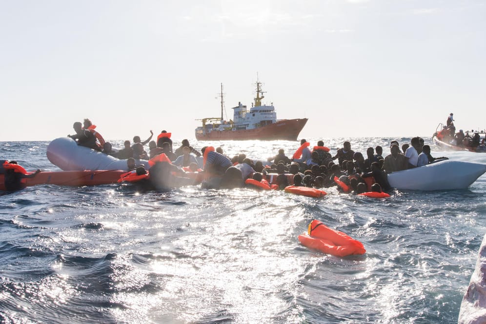 Start in Libyen: Flüchtlinge werden aus dem Mittelmeer geborgen. Meist übernimmt das inzwischen die libysche Küstenwache – und die bringt die Menschen zurück. Auf dem Foto ist im Hintergrund das Rettungsschiff "Aquarius", das nun wieder in die Such- und Rettungszone zurückkehrt.