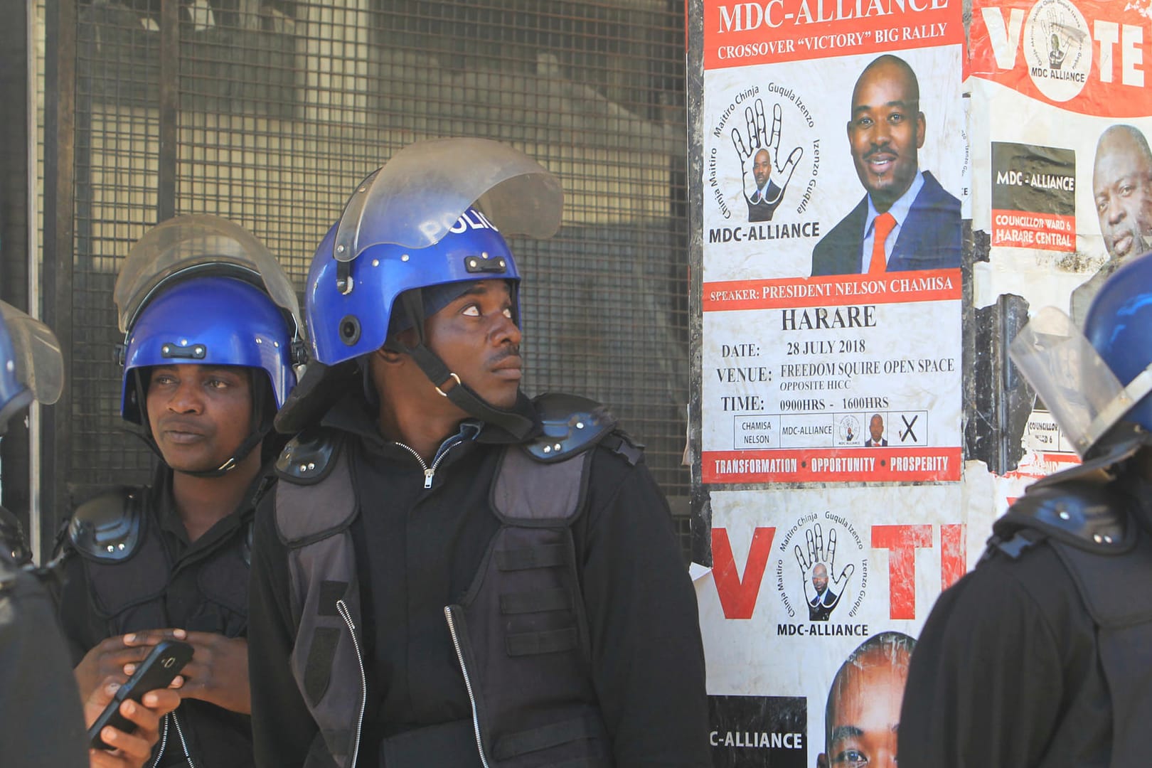 Polizisten vor einem Wahlplakat des wichtigsten Oppositionsführers in Simbabwe: Nach Protesten hat die Polizei die Zentrale der Opposition gestürmt.