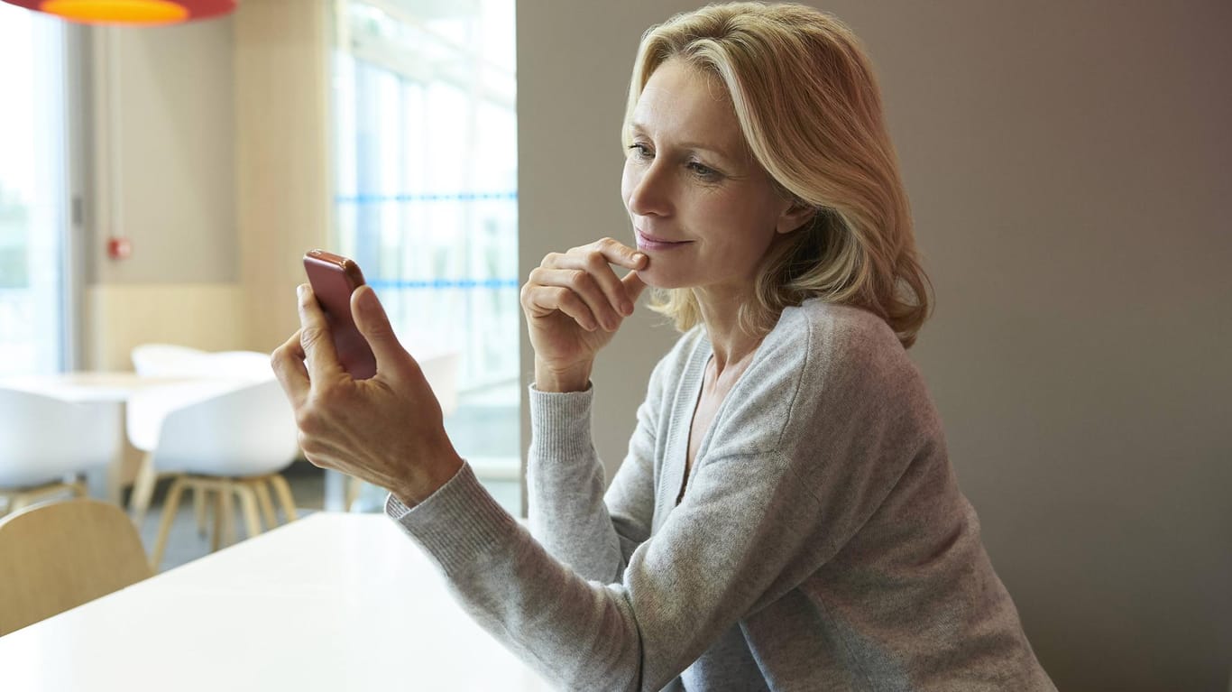 Frau mit Smartphone: Soll man den Handy-Akku immer vollständig auf- und entladen?