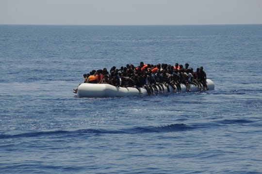Migranten sitzen auf einem überladenen Schlauchboot im Mittelmeer.