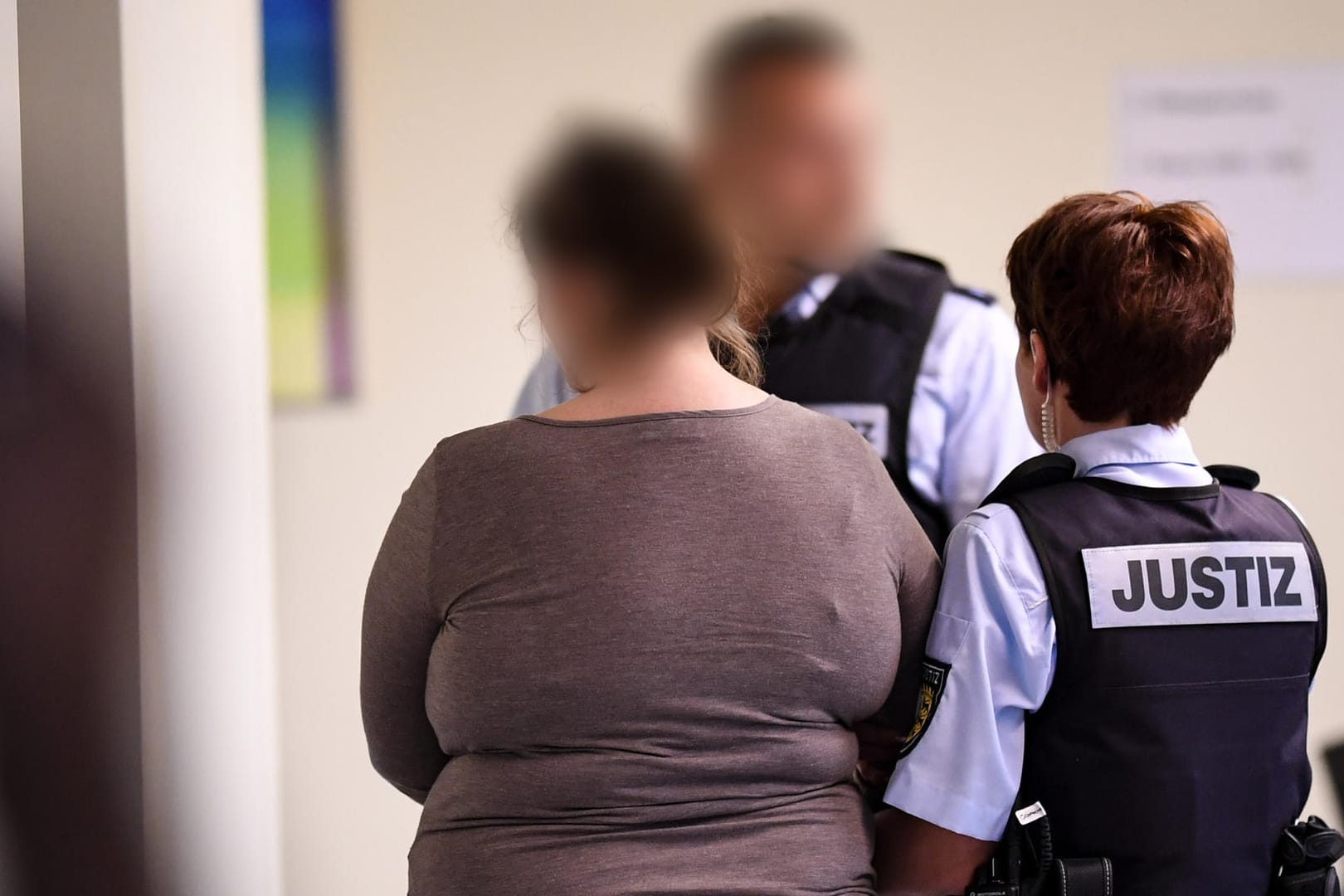 Die angeklagte Mutter (l.) wird aus dem Gerichtssaal geführt: Sie hat gestanden, ihren Sohn pädophilen Männern gegen Geld überlassen zu haben. (Archivbild)