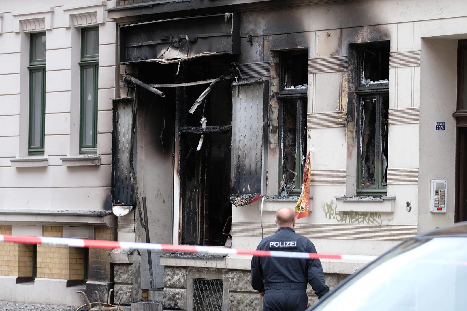 Ein Polizist steht vor einem Mehrfamilienhaus, in dem sich eine Explosion ereignete: Einen technischen Defekt schließt die Polizei bereits aus.