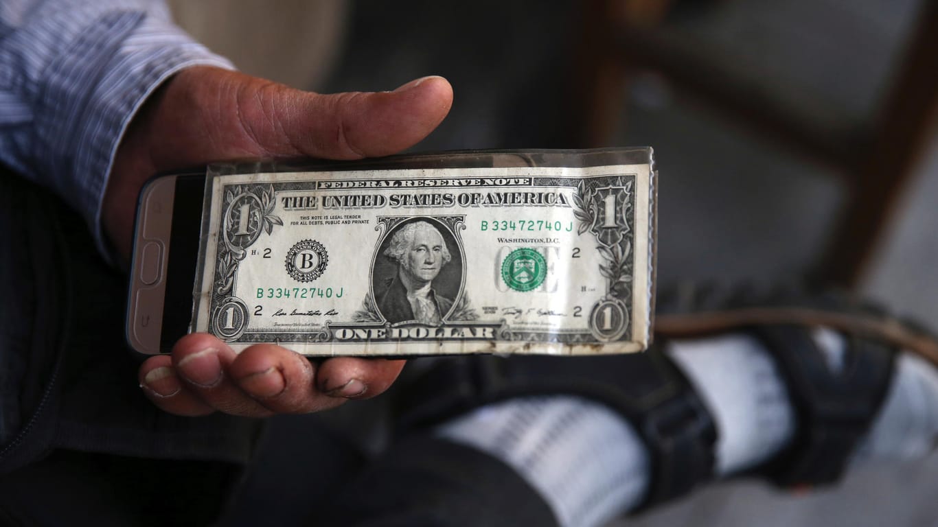 Ein Mann in einer Wechselstube hält eine US-Dollar-Schein: Die iranische Währung befindet sich momentan in einem Rekordtief. (Archivbild)